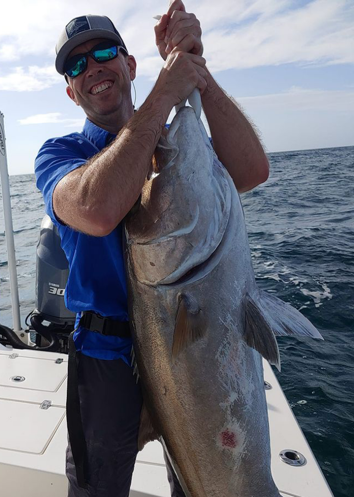 Angler holding a large greater amberjack caught offshore in the Gulf of Mexico on a Sarasota fishing charter
