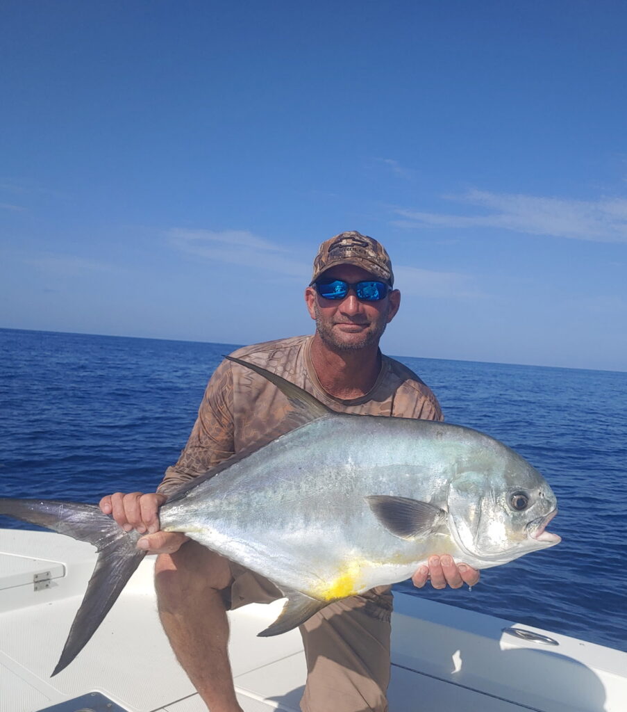 Angler holding a large permit caught on a Sarasota fishing charter with deep blue water in the background