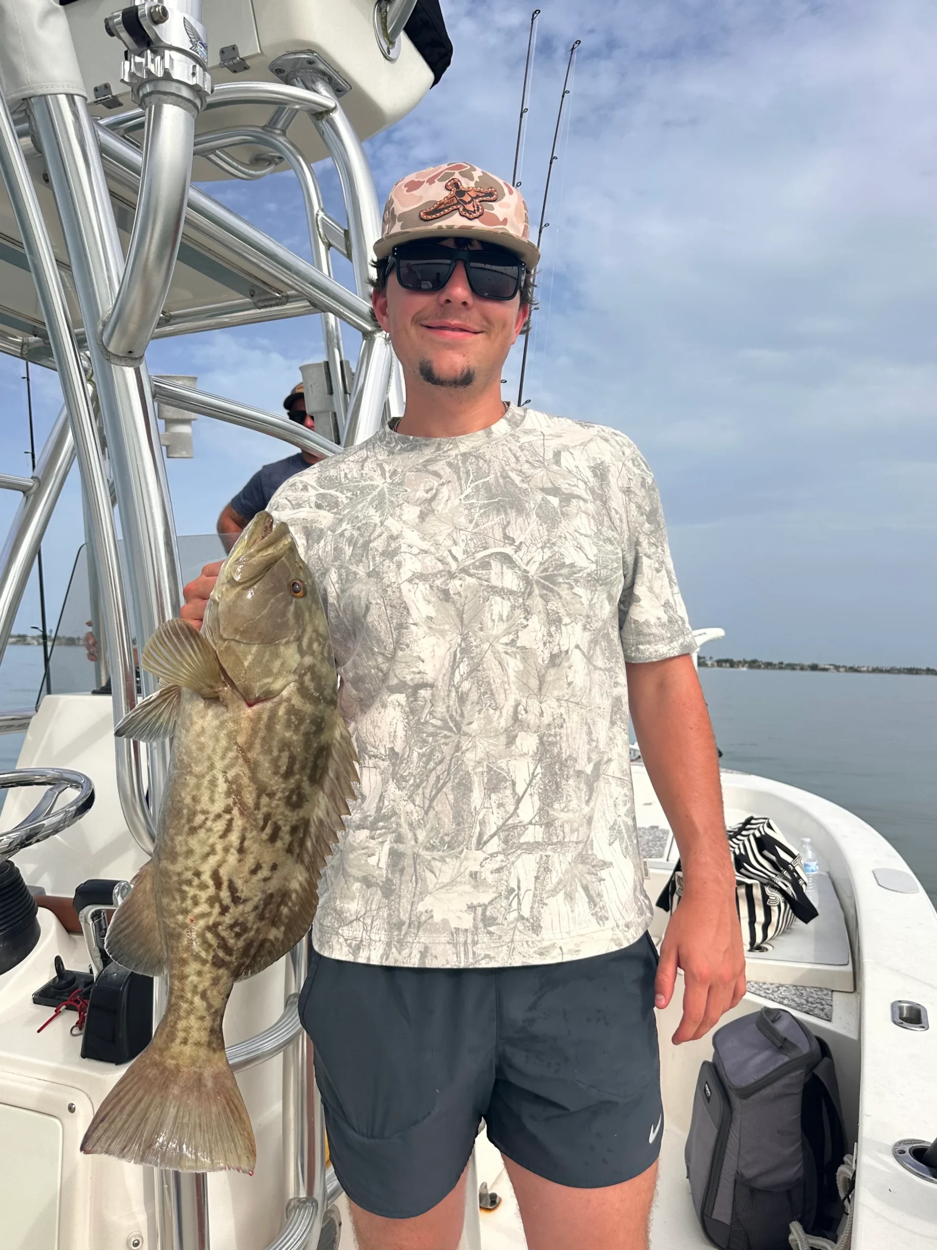 Young angler holding a keeper gag grouper caught on a fishing charter in Sarasota Bay, Florida