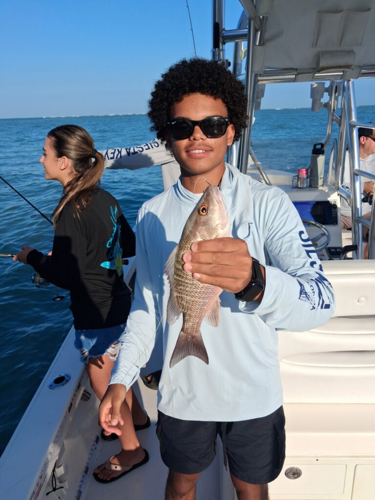 Young angler holding a mangrove snapper caught inshore on a fishing charter in Sarasota Bay, Florida