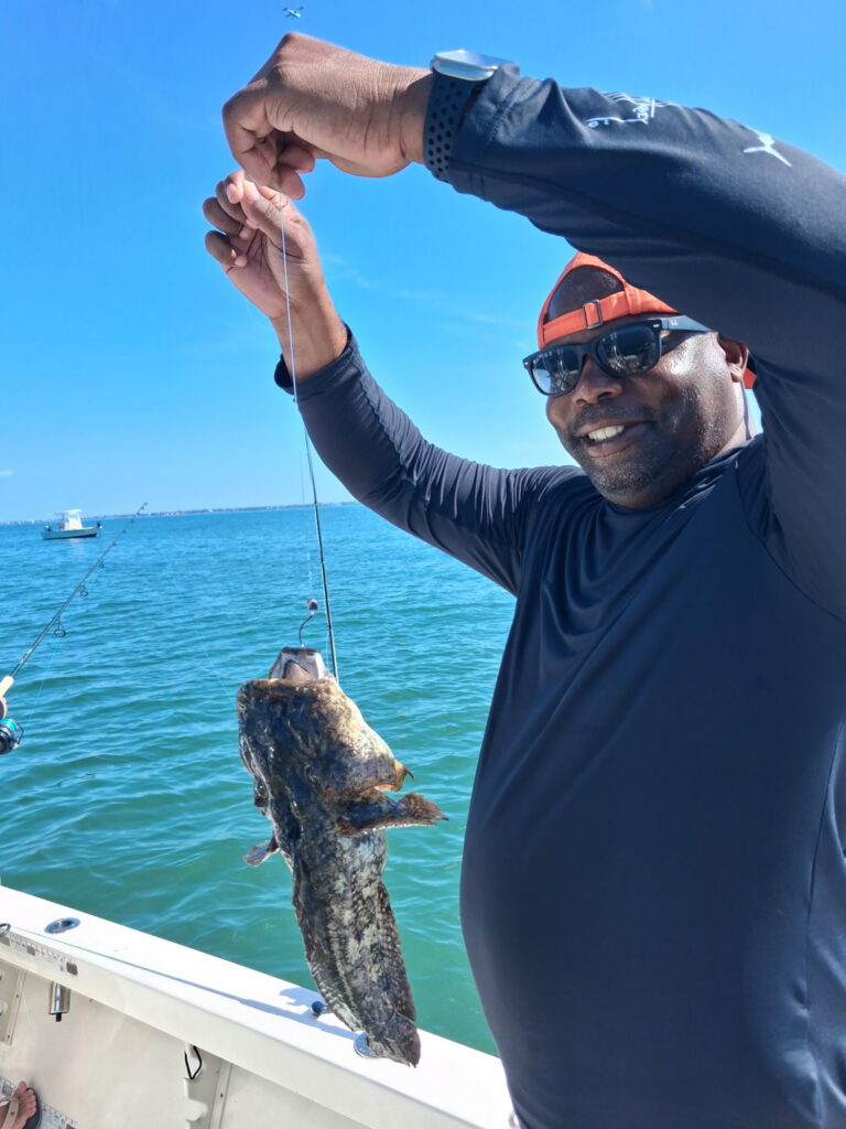 Charter guest holding a Gulf toadfish caught on a fishing charter in Sarasota Bay, Florida