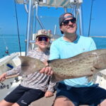 Father and son holding a large gag grouper caught on an inshore fishing charter in Sarasota Bay, Florida