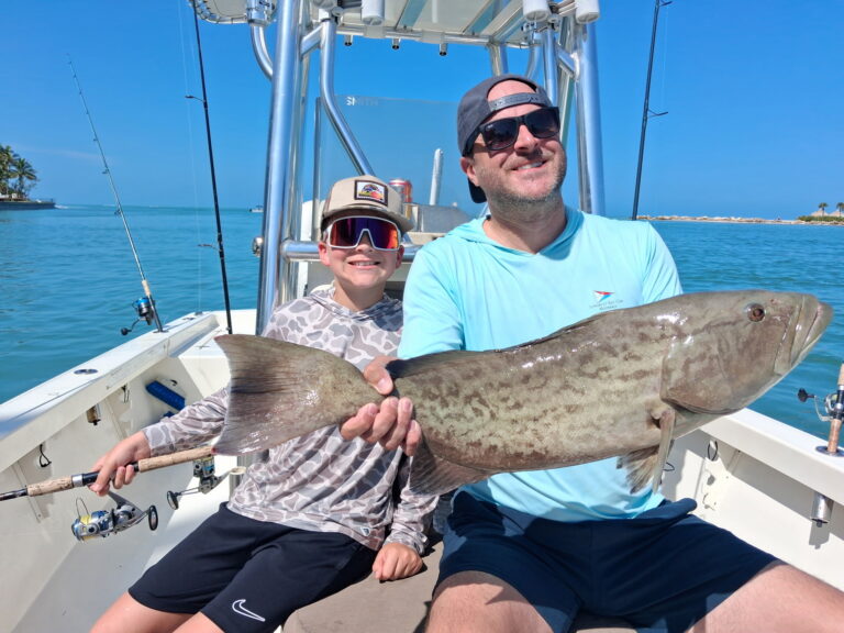 Father and son holding a large gag grouper caught on an inshore fishing charter in Sarasota Bay, Florida