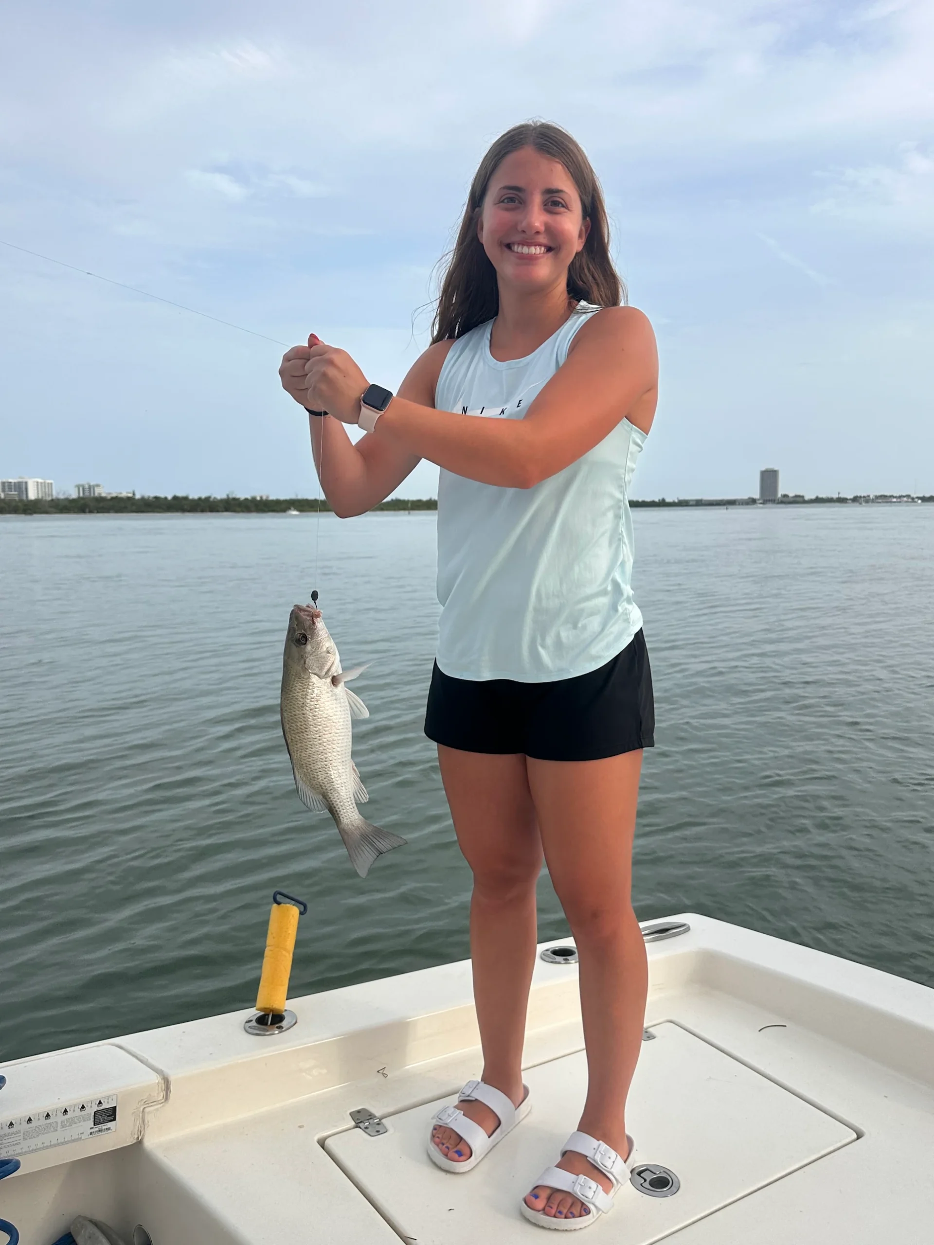 Young woman holding a mangrove snapper caught on a fishing charter in Sarasota Bay, Florida
