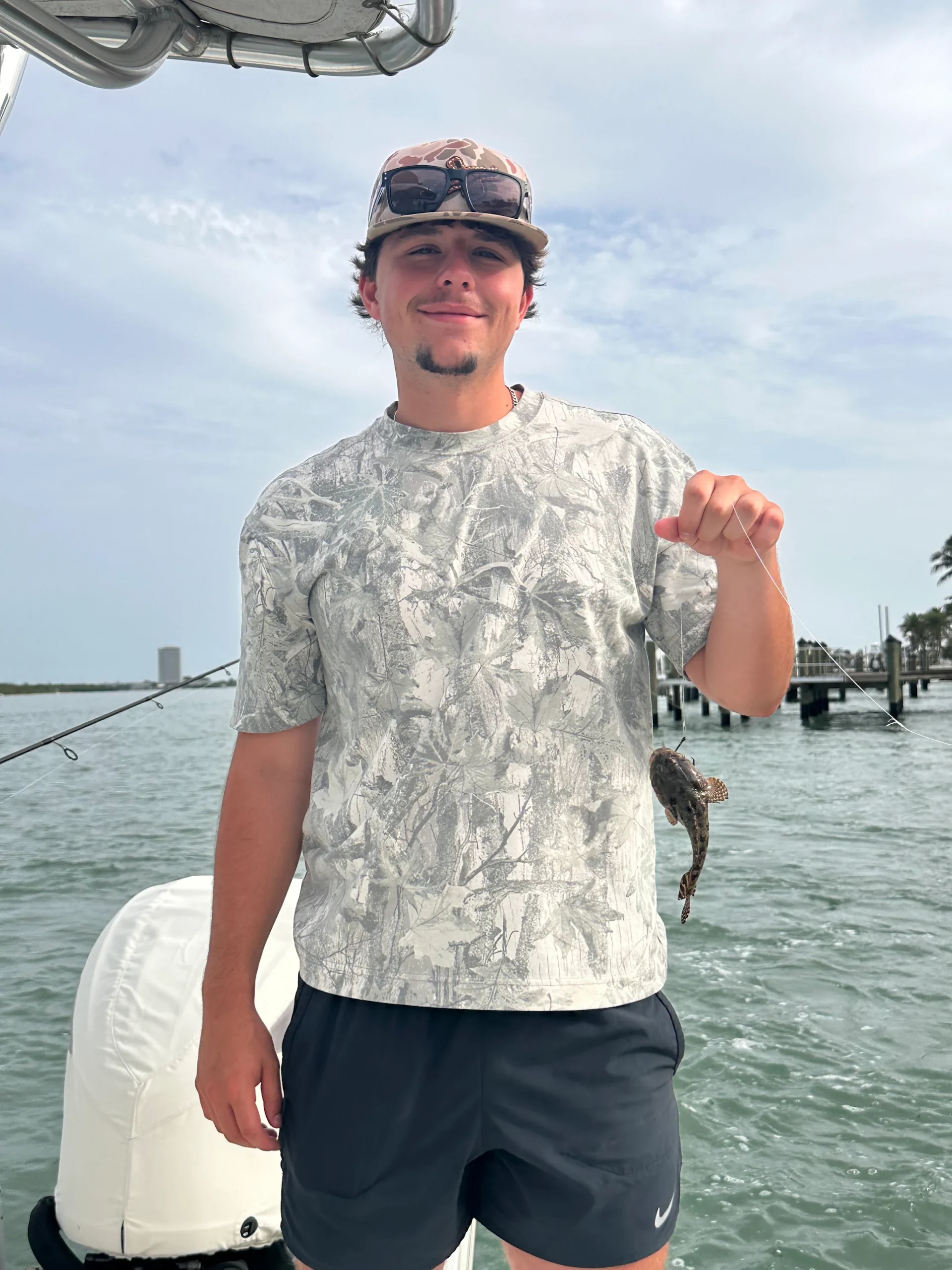 Young angler holding an oyster toadfish caught near dock pilings on a fishing charter in Sarasota Bay, Florida