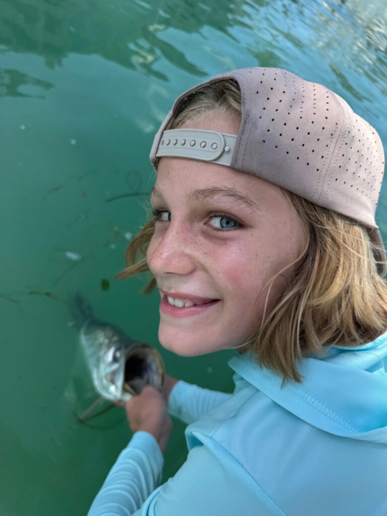 Young angler smiling with a mangrove snapper caught on a family fishing charter in Sarasota Bay, Florida