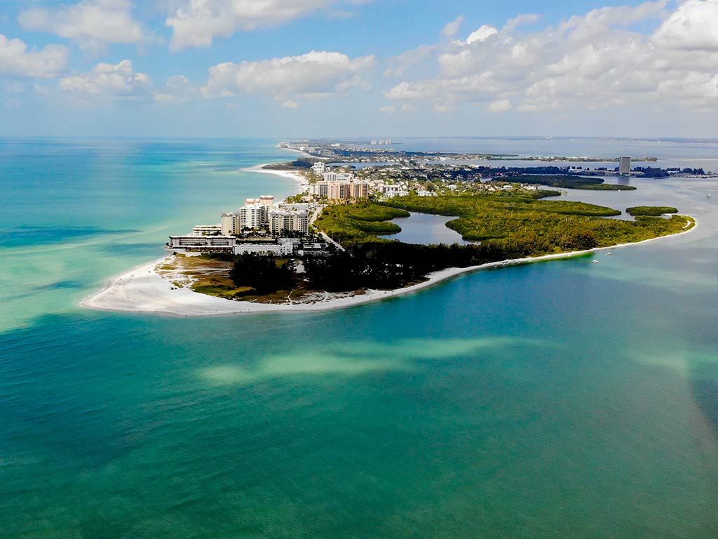 Aerial view of Sarasota barrier island coastline showing turquoise inshore waters, white sand beach, and mangrove shorelines — prime inshore fishing territory